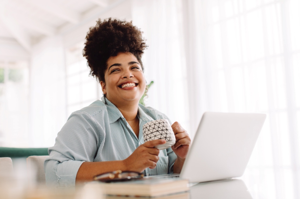 Smiling African-American woman in front of her laptop, representing getting a business loan without already having a business