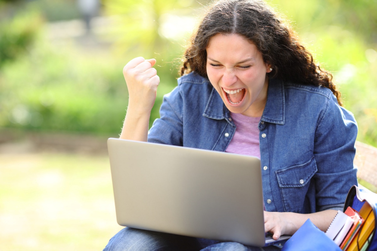 Woman looking at laptop and celebrating, representing fast funding business loans