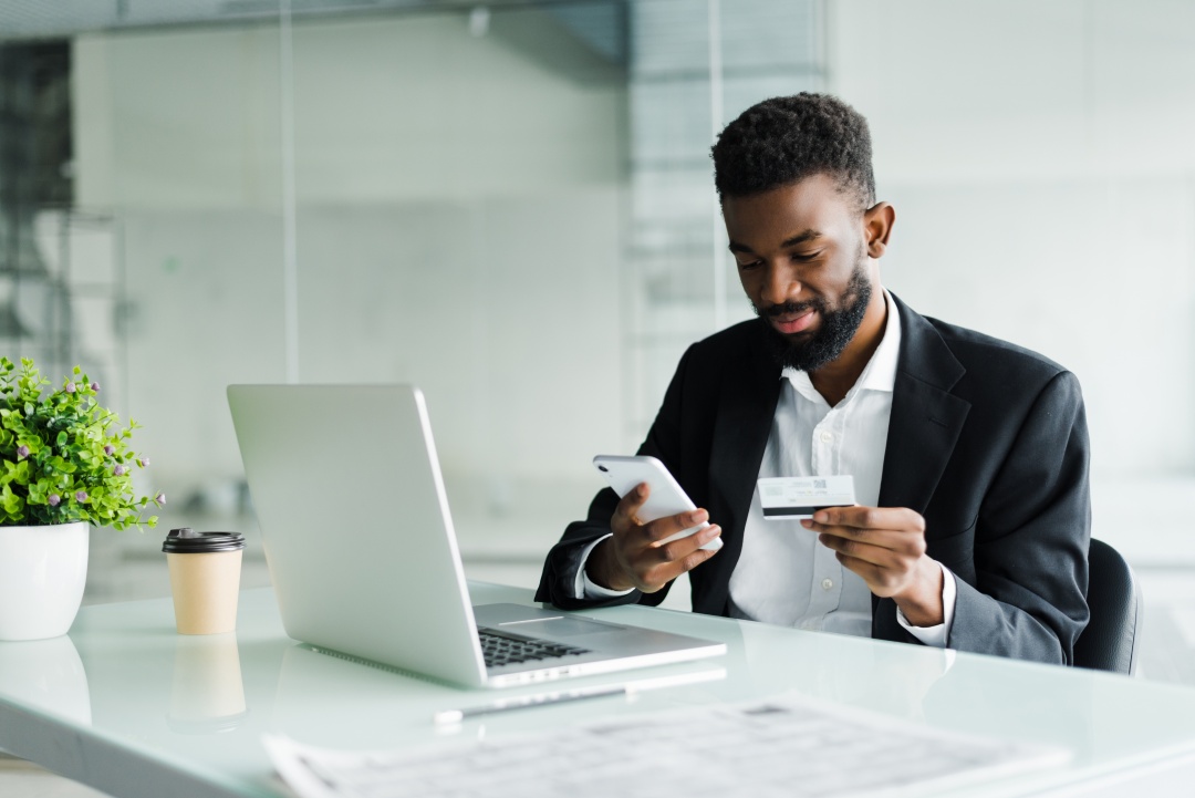 African American man holding a credit card and a mobile phone.